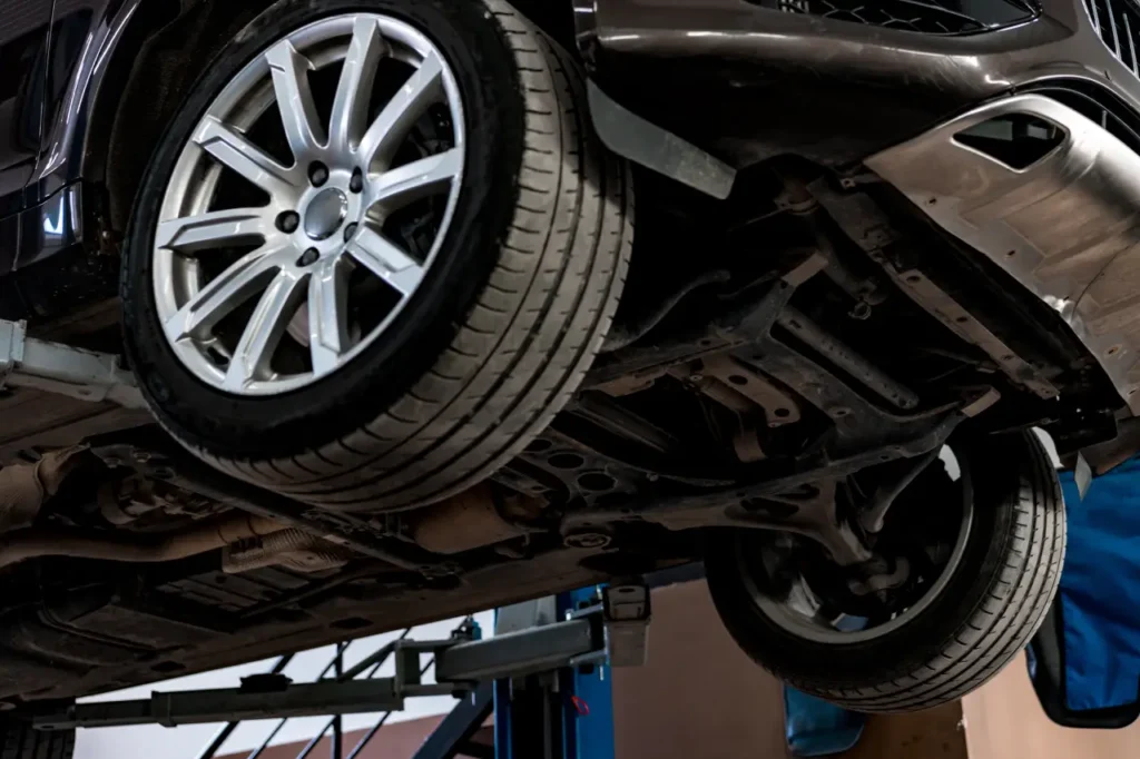 Voiture dans un service de réparation automobile soulevée sur un cric, vue depuis le bas